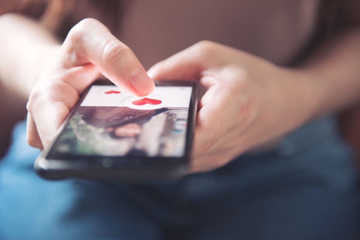 Person using a dating app on a smartphone in a coffee shop