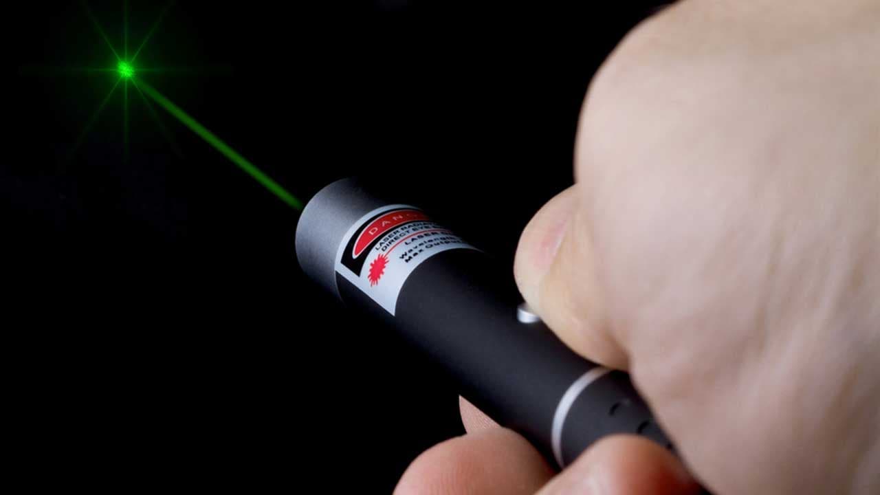A handheld laser pointer projecting a focused red beam, illustrating how laser technology works
